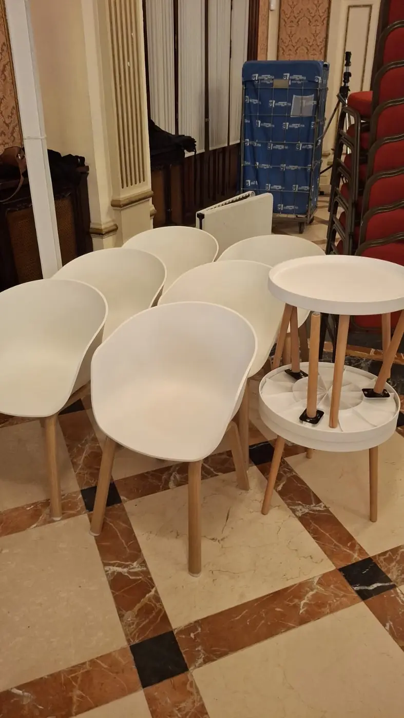 Sillas de diseño y mesas auxiliares entregadas en un salón para un evento en Sevilla